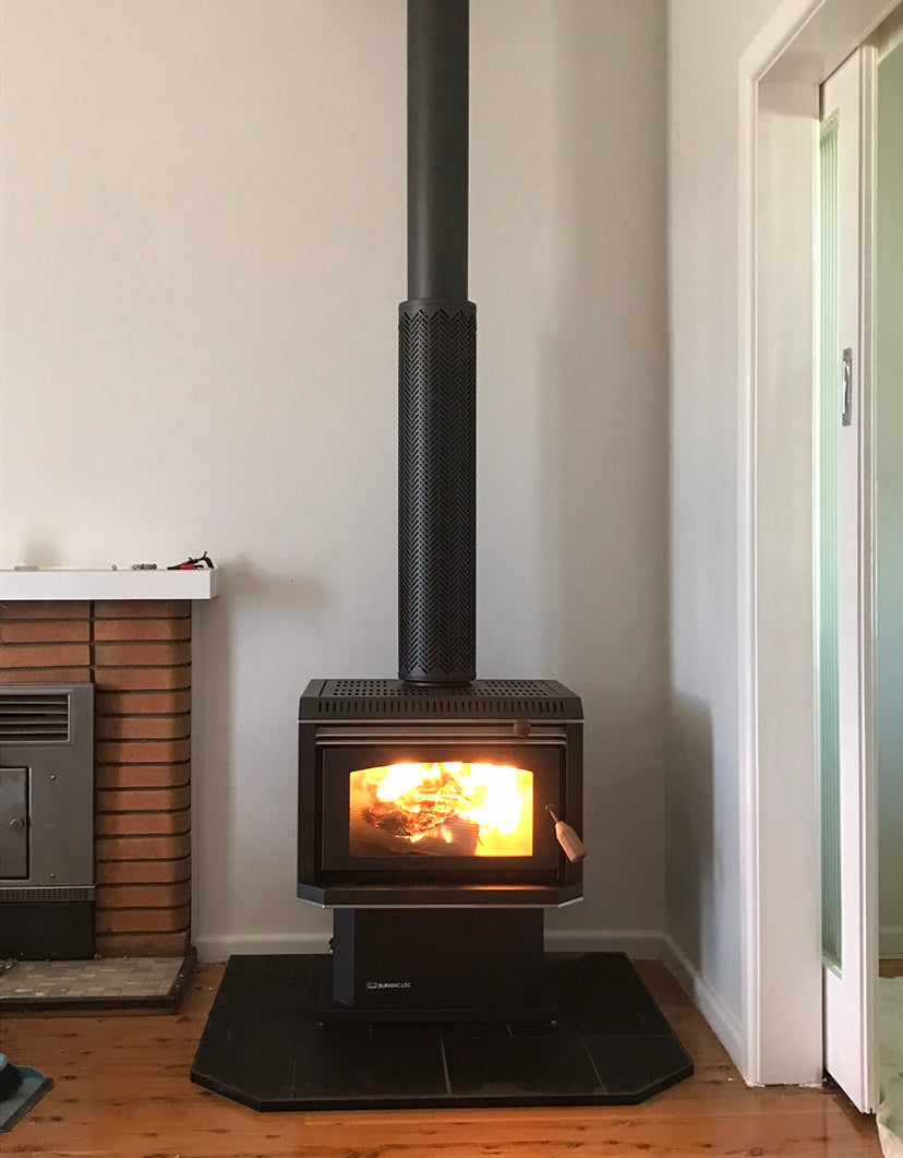 Black metallic Burning Log Turbo 10 wood fireplace with a realistic log design, suitable for cozy indoor heating.