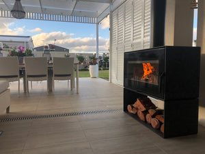 VisionLINE Taurus Double Sided wood fireplace between an indoor living area and alfresco space