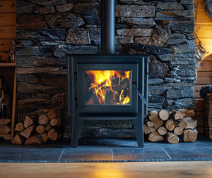 WoodPro WP 200 freestanding wood heater burning in a stone fireplace setting